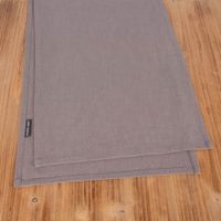 Tischläufer in Leinenoptik in Grau 40x160cm aus Baumwollmischung auf Holztisch, doppelt gelegt mit sichtbarem SCHÖNER LEBEN. Label