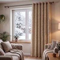 Wohnzimmer mit Thermovorhang Thermochenille INUIT beige mit Ösen, Sessel und Pflanzen vor verschneitem Fenster