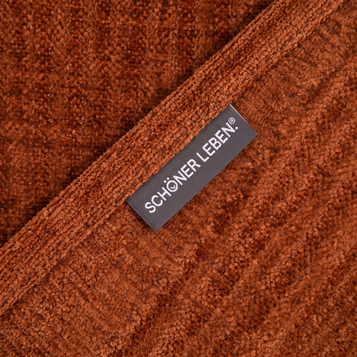 SCHÖNER LEBEN. Thermovorhang Thermochenille Akustik Kälteschutz INUIT terracotta 245cm oder Wunschlänge Nahaufnahme von terracottafarbenem Chenille-Stoff mit sichtbarem Label SCHÖNER LEBEN