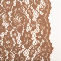 Detailaufnahme brauner Spitzenstoff mit floralen Mustern, zeigt Textur und Randverlauf auf hellem Untergrund.
