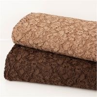 Zwei gerollte Spitzenstoffe in Braun- und Beigetönen, Nahaufnahme der floralen Textur.