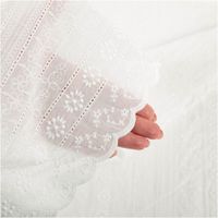 halbtransparenter Baumwollstoff mit feiner floraler Lochstickerei und Streifen, Hand hinter dem Stoff sichtbar
