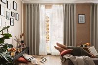 Leinengardine als Gardinenstores mit Verdunklungsvorhängen am bodentiefen Fenster im Wohnzimmer dekoriert