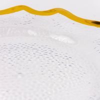 Detailaufnahme transparenter Platzteller mit goldfarbigem Rand und strukturierter Oberfläche