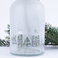 86393-Vase-mit-Haeuserreihe-transparent-oder-halbtransparent-aus-Glas-8x15-5cm-DSC-0518.jpg Detailaufnahme transparente Häuserreihe mit durchscheinenden Tannenzweig im Hintergrund