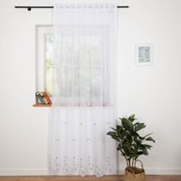 Gardinenstoff Voile Stickerei Fransen Blumen Bogenkante weiß grau beige 280cm Breite Weisser Vorhang an Fenster zeigt dezente Musterung und natürlichen Fall bei Tageslicht.
