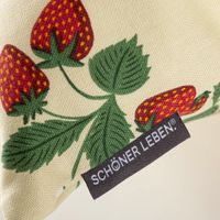 Nahaufnahme der Kissenhülle mit Erdbeeren und grünem Blattwerk, Markenetikett SCHÖNER LEBEN sichtbar.
