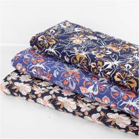 Leichter Viskose Popeline Stoff mit Blumen-Muster in Blau und Orange, 145 cm breit. Weich, atmungsaktiv, hautfreundlich – ideal für Blusen, Kleider & Sommer-Outfits schraege Ansicht des in Szene gesetzten Stoffes