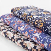 Leichter Viskose Popeline Stoff mit Blumen-Muster in Blau und Orange, 145 cm breit. Weich, atmungsaktiv, hautfreundlich – ideal für Blusen, Kleider & Sommer-Outfits mit anderen Stoffen in Szene gesetzt Nahaufnahme