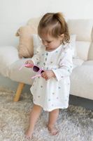 Mädchen trägt ein Kleid aus Musselin Stoff mit buntem Herzchenprint und hält eine pinke Sonnenbrille in der Hand als Kleid verarbeitet