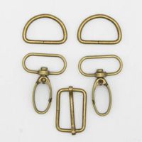 Taschengurt Komplettset 25mm Bronze Matt – 5-teiliges Set mit Karabinerhaken, D-Ringen und Versteller - alle Teile liegen auf einem weißen Hintergrund neben- und übereinander