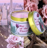 Duftkerze Day of the Flowers von Bomb Cosmetics vor blumiger Kulisse – rosa Sojawachs in dekorativer Metalldose