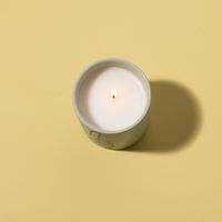 Paddywax Peace Duftkerze von oben – brennend auf gelbem Untergrund