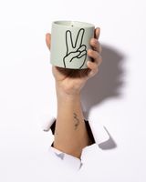 91855-Duftkerze-Impressions-Peace-im-Keramiktopf-Lavender-und-Thyme-von-Paddywax-IM0504EU-20.jpg Hand hält die brennende Duftkerze Peace von Paddywax im mintgrünen Keramiktopf mit Peace-Zeichen
