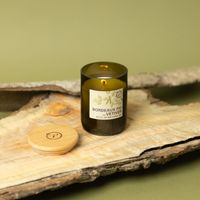 Brennende Eco Green Duftkerze Bordeaux Fig & Vetiver auf Holzunterlage