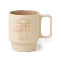 Beigefarbene Keramiktasse mit Shiitake-Pilz-Illustration und goldener Aufschrift „Shiitake Happens“, mit farbigem Innenbereich von DesignWorks Ink USA