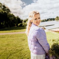 Frau mit fliederfarbener Steppjacke im Sonnenschein