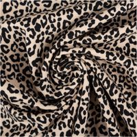 Jerseystoff aus Baumwolle mit klassischem Leopardenmuster in Schwarz auf beigefarbenem Hintergrund, dehnbar und angenehm für Bekleidung geeignet - kunstvoll eingedreht in Falten
