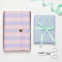 Geschenkverpackung mit Seidenpapier rosa-flieder gestreift, daneben Geschenk mit Schleife und Schere