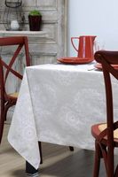 Esszimmertisch mit naturfarbener Tischdecke aus Baumwollstoff, verziert mit weißen Kreisornamenten und kleinen roten Punkten. Rote Stühle und Geschirr ergänzen das natürliche Ambiente.