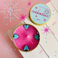 Pinke Duftkerze Celebrations von Bomb Cosmetics in Metalldose mit türkisfarbenem Deckel und Herzverzierungen