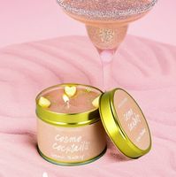 92403-Duftkerze-Cosmo-Cocktail-in-der-Metalldose-handgemacht-von-Bomb-Cosmetic--Screenshot-2025-08-16-134223.jpg Geöffnete Cosmo Cocktail Candle neben Cocktailglas mit rosa Glitzerdrink