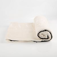 Superflauschige Kuscheldecke Jade in Dove White, 130x180 cm groß, zusammengerollt mit schwarzem Kettelrand und Verpackungsband von Unique Living - ausgerollt linke Seite