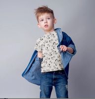 Kind trägt T-Shirt aus Jersey Stoff Snoopy Peanuts weiß mit Schwarz-Weiß-Motiven, kombiniert mit Jeansjacke