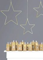 Hängende goldene Metallsterne als Weihnachtsdeko über Adventskalender