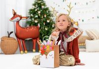 Kind mit Geschenktüte Reh vor einem Weihnachtsbaum