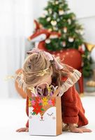 Mädchen schaut in Geschenktüte Reh mit buntem Aufdruck