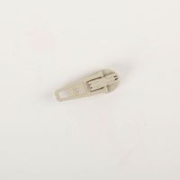 Zipper in Beige lackiert, 25 mm – kompakter Schieber aus Feinzinkdruckguss mit trapezförmigem Zuggriff und seitlicher Arretierautomatik, präzise gefertigt für Reißverschlüsse in Textilien und Taschen - Detailaufnahme