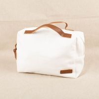 Praktische, unifarbene Kosmetiktasche Travel aus weißem Baumwoll-Canvas. Die Tasche mit Reißverschluss und braunen Tragegriffen ist 26 mal 12 mal 17 Zentimeter groß - Vollansicht mit Farbkontrast