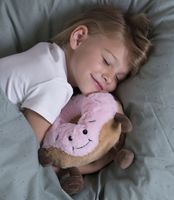 Kind kuschelt im Bett mit Warmies® Donut Wärmestofftier rosa