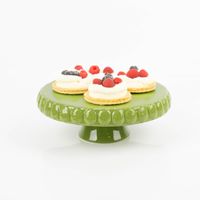 Handgearbeitete Tortenplatte aus Steingut von Boltze. Der leuchtend grüne Kuchenständer mit einem glasierten Relief-Rand ist 24,8 Zentimeter im Durchmesser und lebensmittelecht - mit Toertchen praesentiert