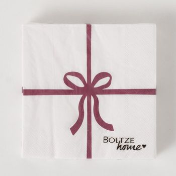 Packung weißer Servietten mit roter Schleife, quadratisch, Markenlogo unten rechts.