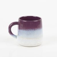 Handbemalte Keramiktasse der Serie Mojave von Sass & Belle. Die bauchige Tasse mit Henkel hat eine glänzende, gesprenkelte Glasur in Lila, die nach unten in Weiß übergeht. Sie ist eine dekorative und trendige Ergänzung für die Küche - Vollansicht