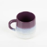 Handbemalte Keramiktasse der Serie Mojave von Sass & Belle. Die bauchige Tasse mit Henkel hat eine glänzende, gesprenkelte Glasur in Lila, die nach unten in Weiß übergeht. Sie ist eine dekorative und trendige Ergänzung für die Küche - Detailaufnahme von ob