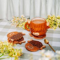 Rustikales Untersetzer-Set von Sass & Belle aus dunkelbraunem Mangoholz. Die quadratischen Untersetzer sind mit einer stilisierten Highland Cow in dunkelbrauner Farbe graviert. Das 4er Set schützt Oberflächen und dient als dekorativer Hingucker -Tischszene
