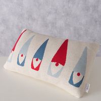 Weihnachtskissen Wichtel aus gestrickter Baumwolle, präsentiert mit fünf stilisierten Wichtelmotiven in Rot und Blau; rechteckige Kissenhülle von Boltze im Format 30×50 cm - in Szene auf einem Tisch mit hellem Hintergrund