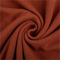 Strickstoff aus 100 % Baumwolle in warmem Rostton, 135 cm breit – weich, atmungsaktiv und ideal für herbstliche Strickmode und Accessoires - kunstvoll eingedreht in Falten