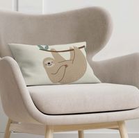 Kissenhülle Faultier 30x50cm auf hellem Sessel, dekoratives Wohnaccessoire aus Baumwolle