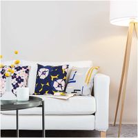 Weißes Sofa mit Kissen aus grafischen und floralen Stoffen in Blau, Gelb und Rosa, daneben eine Stehlampe