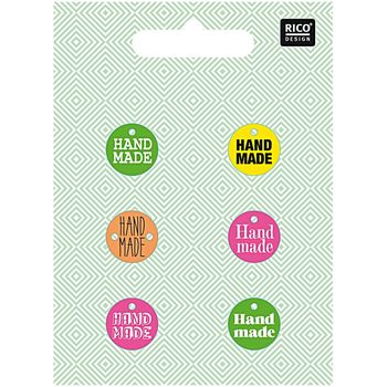 Sechs bunte Knöpfe mit der Aufschrift „Handmade“ in Neonfarben (Grün, Gelb, Orange, Pink) auf gemustertem Hintergrund – Rico Design Set à 6 Stück.