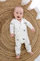 93222-Jersey-Stoff-Baumwolljersey-Leo-beige-schwarz-1-50m-Breite-23519-051-2.jpg Baby in weißem Strampler aus Baumwolljersey mit Dackel-Muster, liegend auf einer Bastmatte, lächelnd in die Kamera