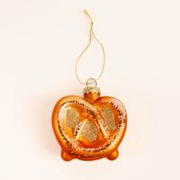 Dekorativer Weihnachtshänger in Form einer glänzenden Brezel in warmem Braun und Goldtönen. Mit einer Größe von 7,5 x 7,5 cm und glitzernden Details ist dieser Anhänger ein besonderer Blickfang für Ihren Tannenbaum - Vollansicht