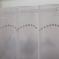 Nähfreie Scheibengardine als Meterware in klassischem Weiß mit beigen Stickereien. Die feinen Pünktchen-Motive und Wellenlinien zieren den transparenten Stoff in 50 cm Höhe. Ein dekorativer Fensterschmuck - Nahaufnahme