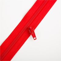 YKK Schieber für Reißverschluss-Meterware mit 5-mm-Kunststoffspirale in 3 cm Breite, präsentiert in kräftigem Rot; einzelner Zipper als passender Verschluss - neben passendem Reissverschluss praesentiert