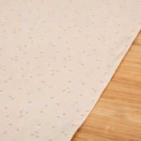 Detailaufnahme des naturfarbenen Tischläufers mit goldenen Punkten auf Holzoberfläche.