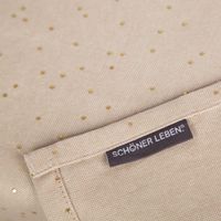 SCHÖNER LEBEN. Markenlabel auf naturfarbenem Tischläufer aus Baumwoll-Canvas mit goldenen Punkten.